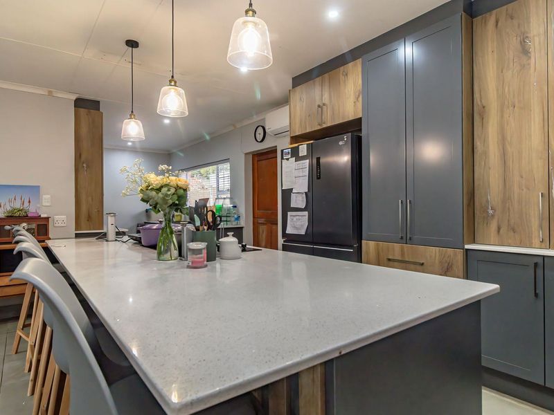 Modern kitchen featuring a large central island with quartz countertops, two-tone cabinetry, and stylish pendant lighting.