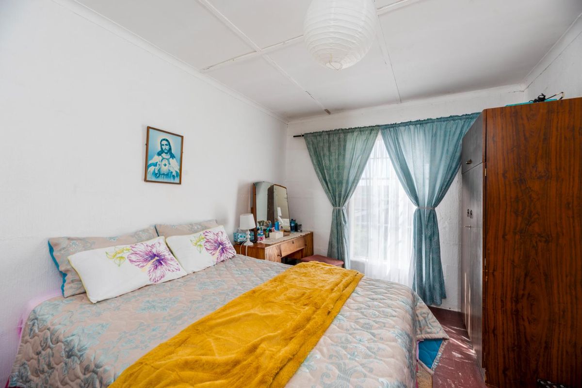 A functional bedroom featuring white walls, a window with curtain tracks, and a ceiling with visible panel joints.