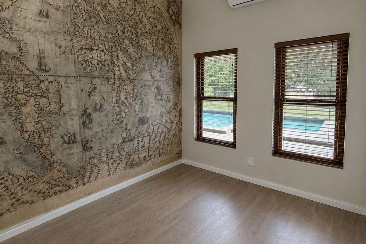 A bright, empty bedroom featuring laminate flooring, a split-system air conditioner, and a large decorative map feature wall with views of the pool area.