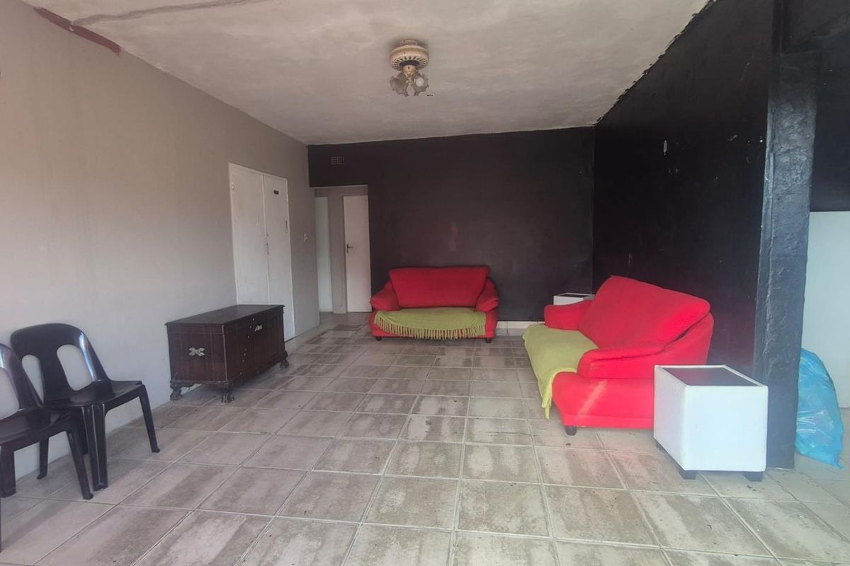 A spacious living area featuring tiled flooring, a ceiling fan, and neutral wall finishes, providing a blank canvas for potential interior updates.