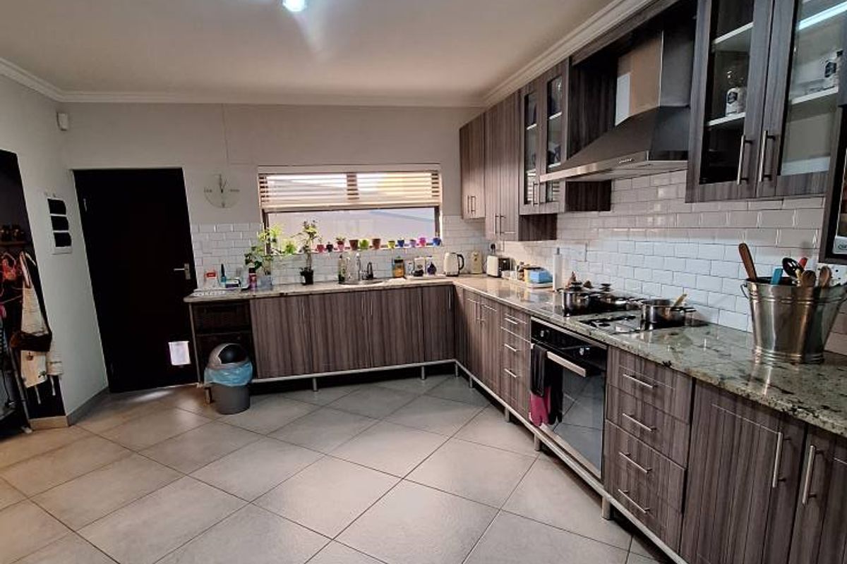 A functional kitchen featuring modern wood-grain cabinetry, granite countertops, a subway tile backsplash, and integrated stainless steel appliances.