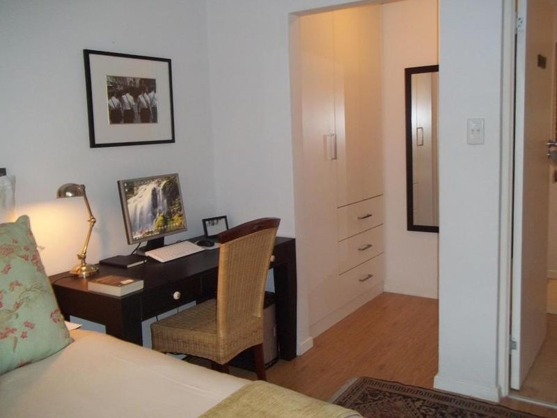 A bedroom featuring laminate flooring and a built-in wardrobe with integrated drawers, providing functional storage space.