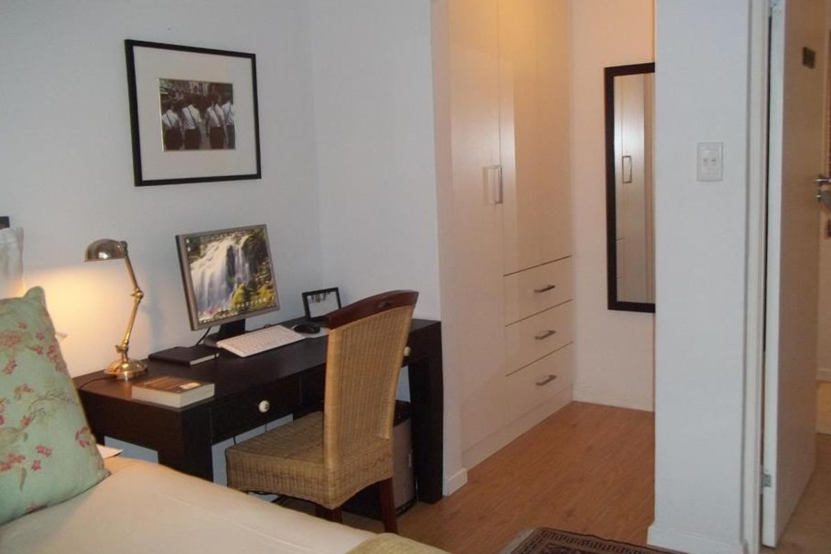 A bedroom featuring laminate flooring and a built-in wardrobe with integrated drawers, providing functional storage space.