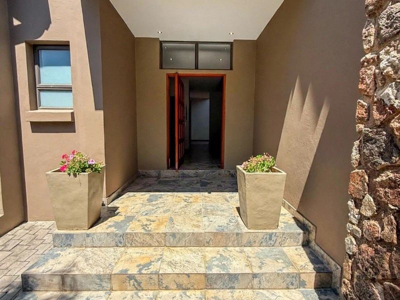 A welcoming front entrance featuring stone cladding, tiled steps, and a modern covered porch with recessed lighting.