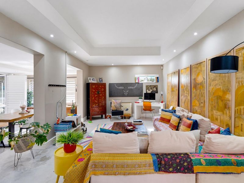 Spacious open-plan living area featuring a tray ceiling with recessed lighting and neutral tiled flooring, seamlessly connecting to the adjacent dining space.