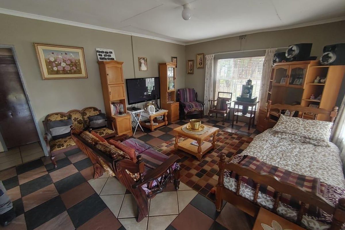 A living room featuring checkered floor tiles and coved ceilings, offering a functional space that would benefit from modern updates and cosmetic improvements.