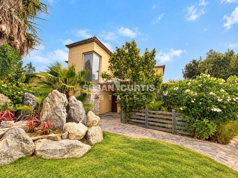 Front exterior view of a townhouse featuring a stone pathway, landscaped garden, and stucco facade with a tiled roof.