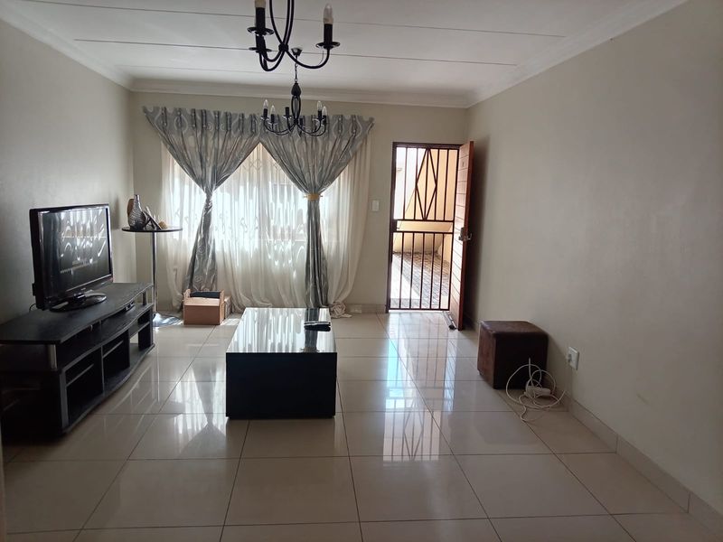 A living room featuring tiled flooring, a security gate at the entrance, and decorative ceiling lighting.