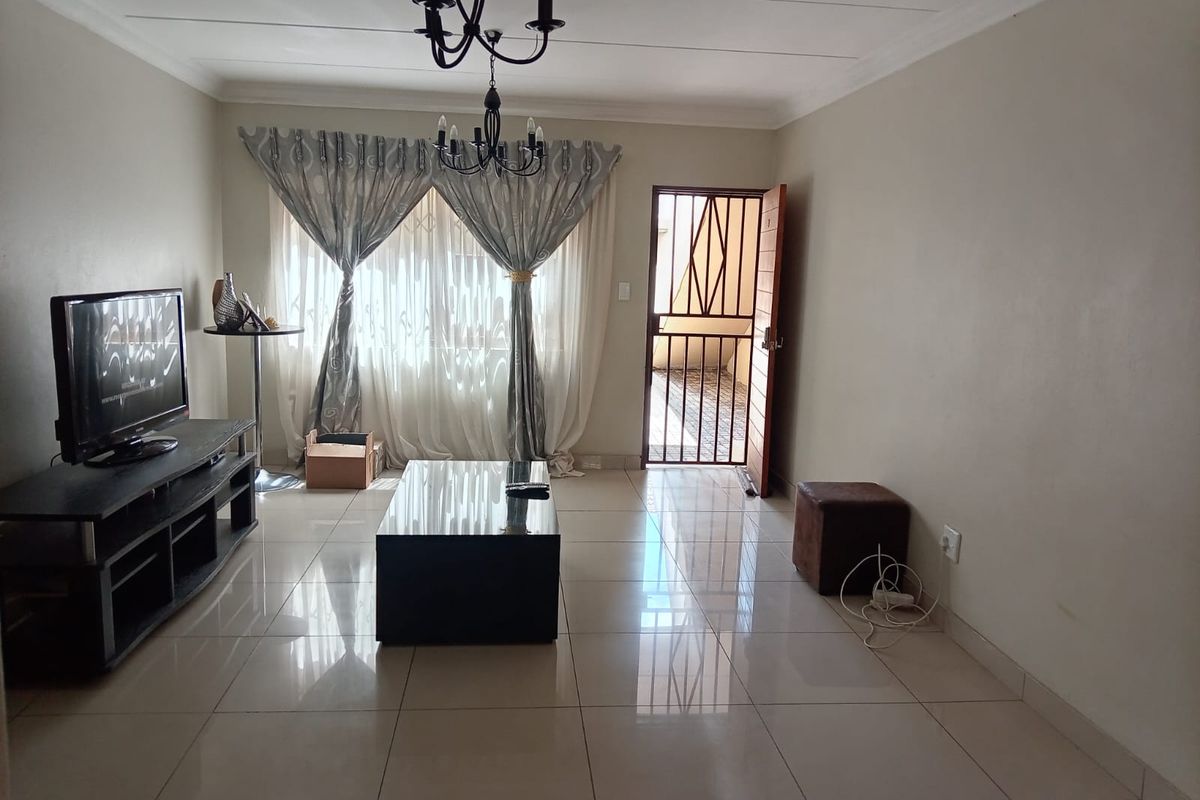 A living room featuring tiled flooring, a security gate at the entrance, and decorative ceiling lighting.