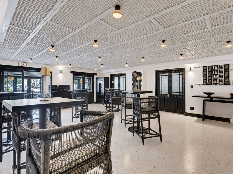 A well-maintained open-plan retail or commercial space featuring a unique decorative drop ceiling, modern epoxy flooring, and elegant double glass panel doors.