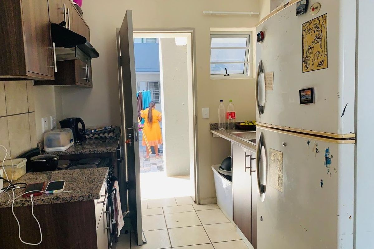 Compact kitchen featuring granite countertops, dark wood-look cabinetry, and tiled flooring with direct access to an outdoor area.
