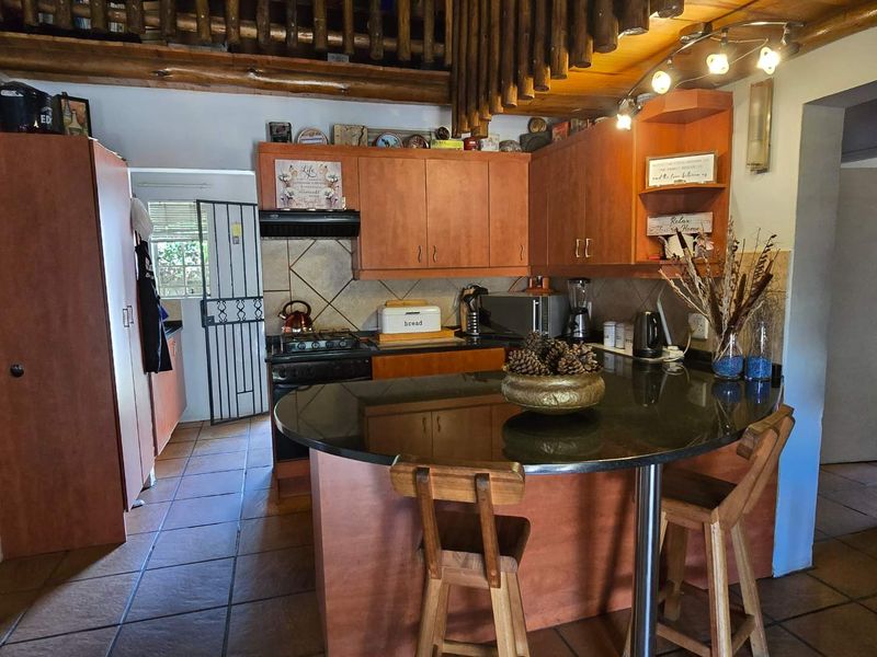 A functional kitchen featuring wooden cabinetry, granite countertops, a breakfast nook, and exposed timber ceiling beams, offering a warm and traditional aesthetic.