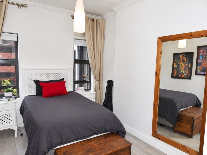 A well-maintained bedroom featuring crown molding, laminate flooring, and dual casement windows providing natural light.
