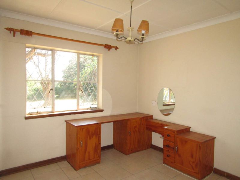 A bedroom featuring tiled flooring, a leaded glass window, and a built-in wooden vanity unit.