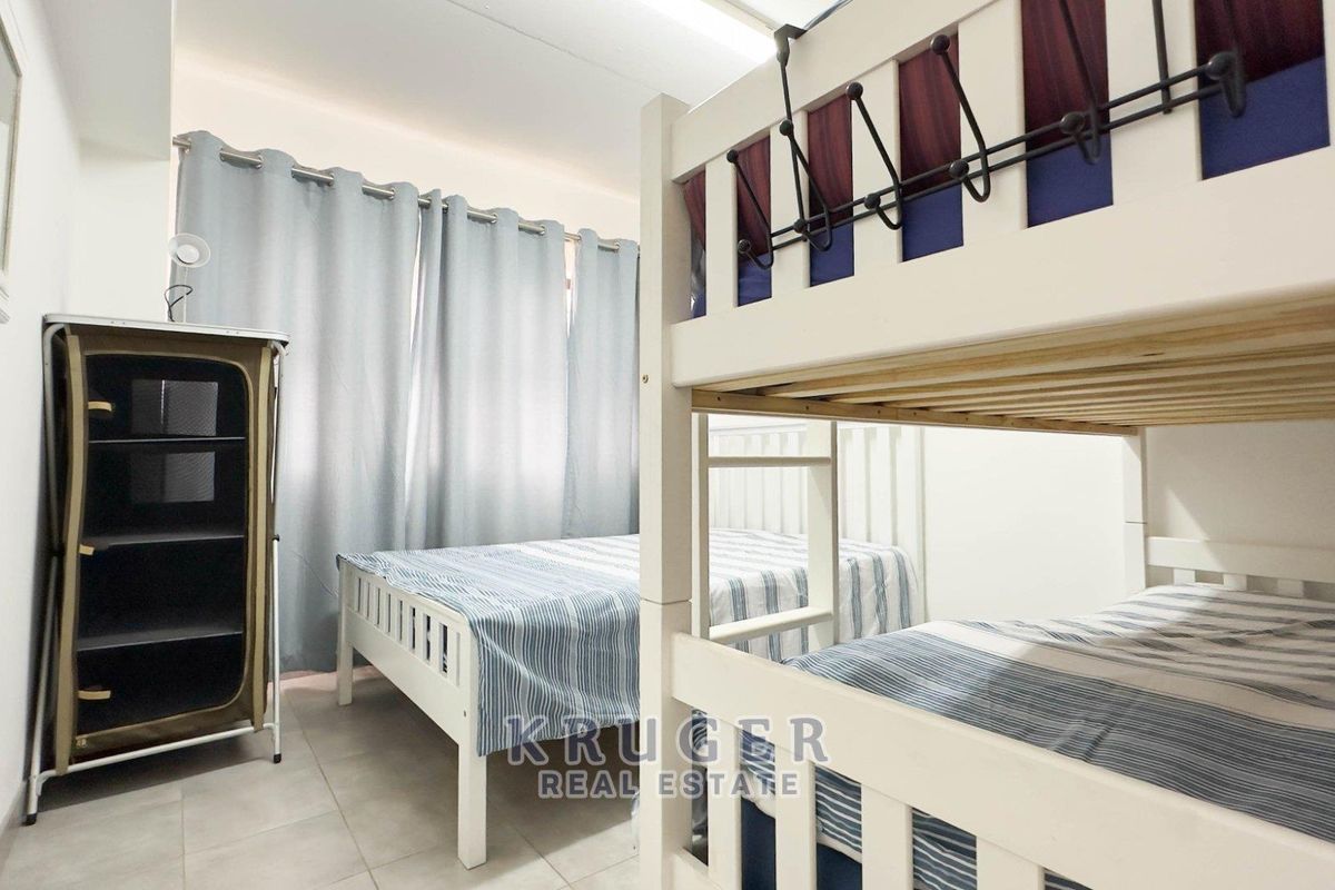 A functional bedroom featuring tiled flooring and neutral wall finishes, providing a practical space for sleeping arrangements.