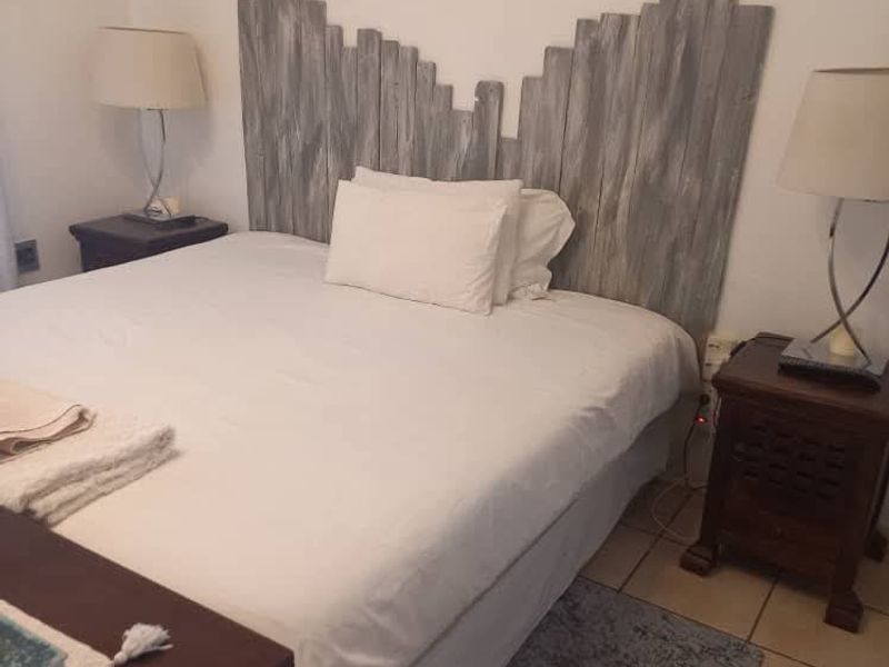 A bedroom featuring tiled flooring and a rustic wooden headboard.
