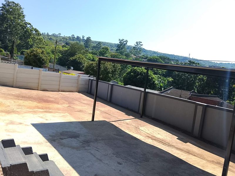 An expansive outdoor patio area featuring a concrete surface, perimeter boundary walls, and a metal support structure, offering elevated views of the surrounding landscape.