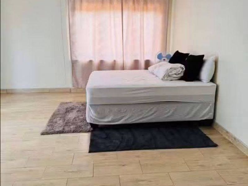 A bedroom featuring wood-look tile flooring and a window with curtains.