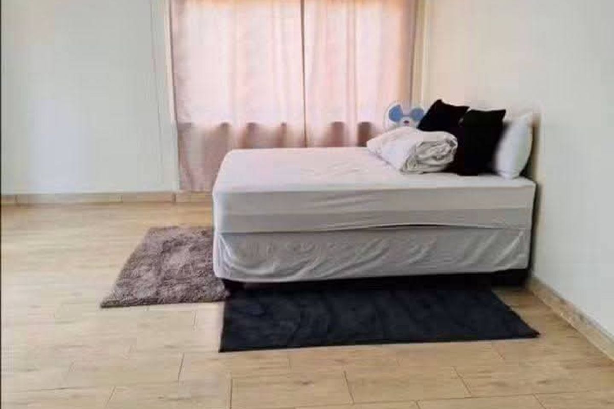 A bedroom featuring wood-look tile flooring and a window with curtains.