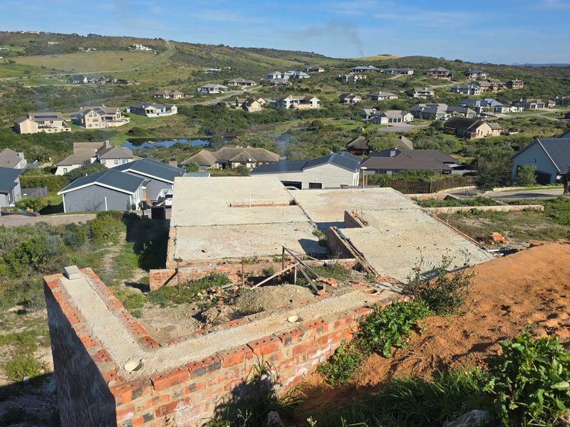 Aerial view of a residential property under construction, showing the concrete slab foundation and brick wall structure in a suburban estate setting.