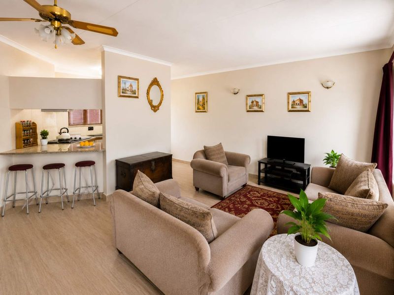 Open-plan living area featuring a kitchen with a granite breakfast bar, neutral wall finishes, and a ceiling fan, creating a functional and connected space.
