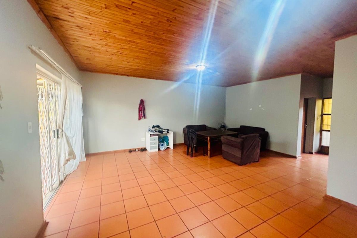 Spacious living area featuring terracotta floor tiles and a timber-clad ceiling, with sliding glass doors providing access to the exterior.