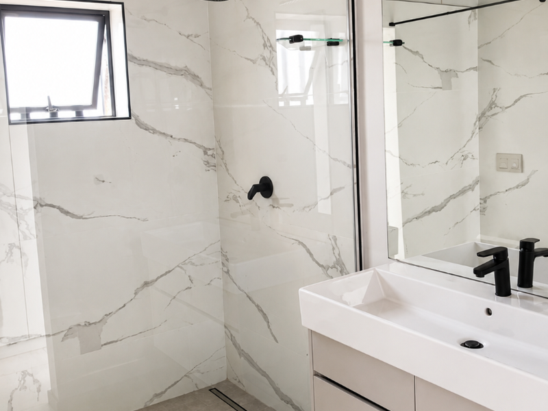 Modern bathroom featuring a walk-in shower with marble-look tiling, black matte fixtures, and a sleek vanity cabinet with a large mirror.