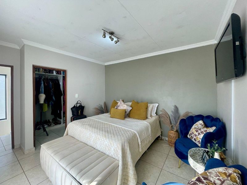 A bedroom featuring tiled flooring, a built-in closet, and ceiling track lighting, with visible water staining on the ceiling.