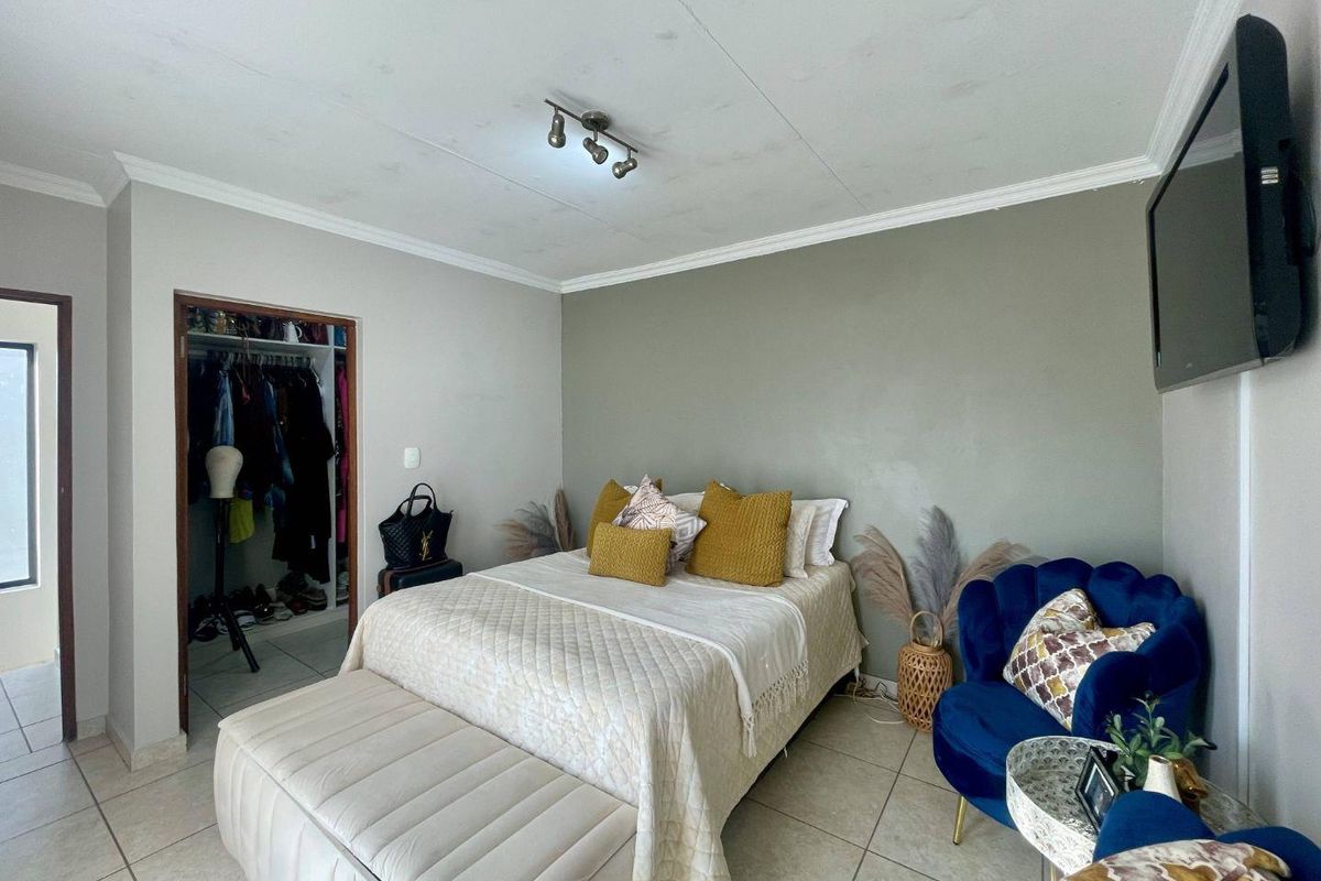 A bedroom featuring tiled flooring, a built-in closet, and ceiling track lighting, with visible water staining on the ceiling.