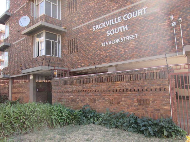 Front exterior view of Sackville Court South apartment building, featuring face brick facade, secure perimeter wall with electric fencing, and gated entrance.