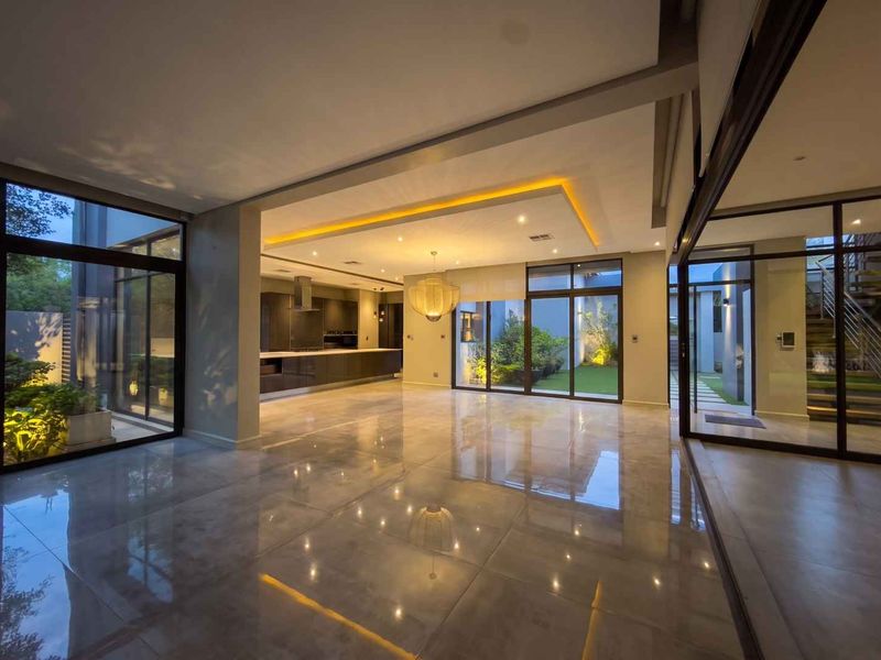 Spacious open-plan living area featuring high-end finishes, large format tiling, recessed lighting, and seamless indoor-outdoor flow through expansive glass sliding doors.