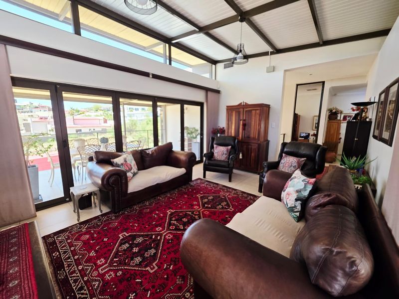 Spacious living room featuring high exposed beam ceilings, clerestory windows for natural light, and large sliding glass doors opening to an outdoor patio area.