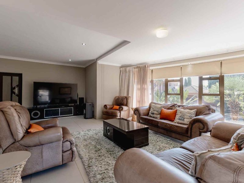 Spacious living room featuring large windows that provide ample natural light, neutral wall tones, and modern tiled flooring.