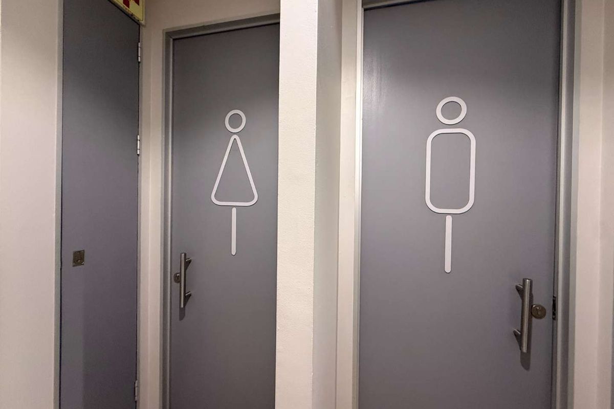 A clean, functional office restroom area featuring clearly marked gender-specific doors with modern lever handles.