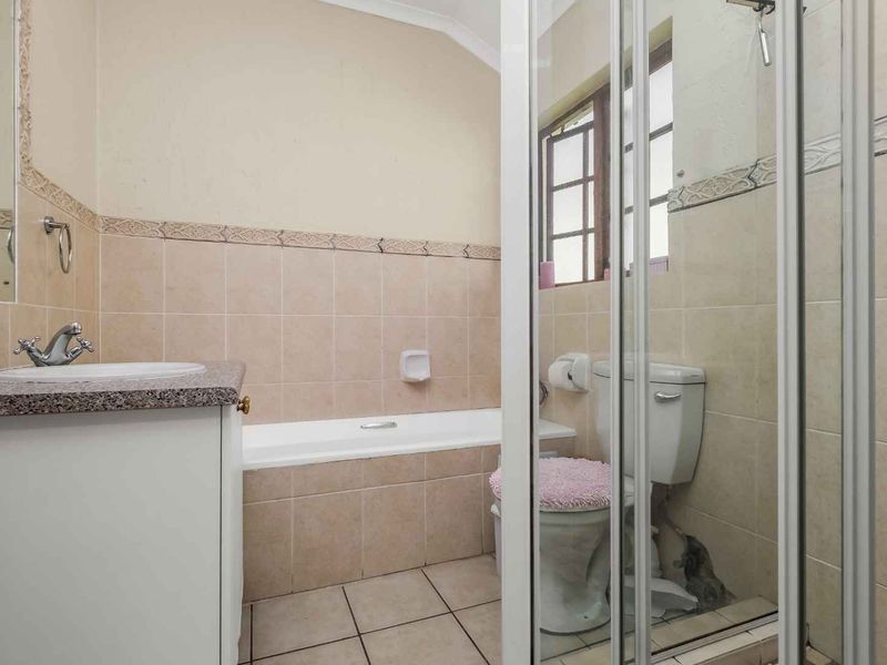 A functional bathroom featuring a built-in vanity, bathtub, separate shower enclosure, and tiled finishes throughout.