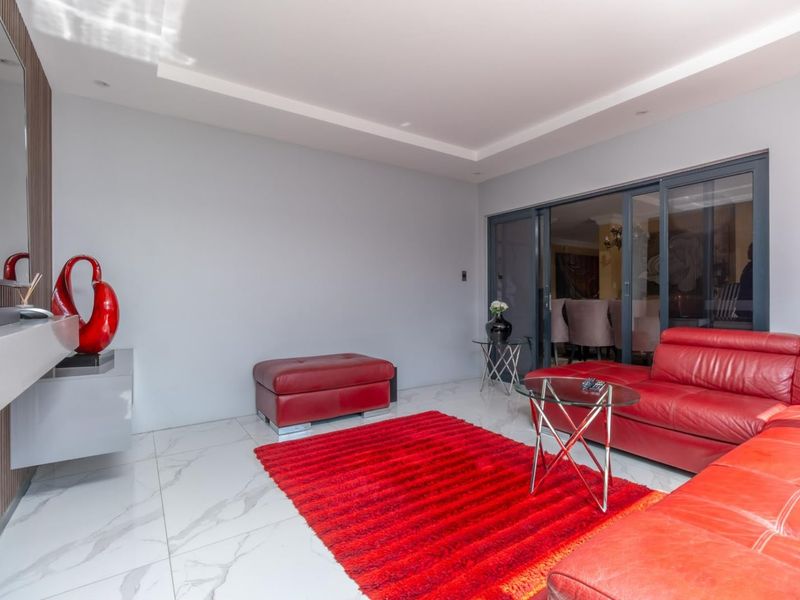 Modern living room featuring large-format marble-look floor tiles, recessed ceiling lighting, and sliding glass doors leading to an adjacent space.