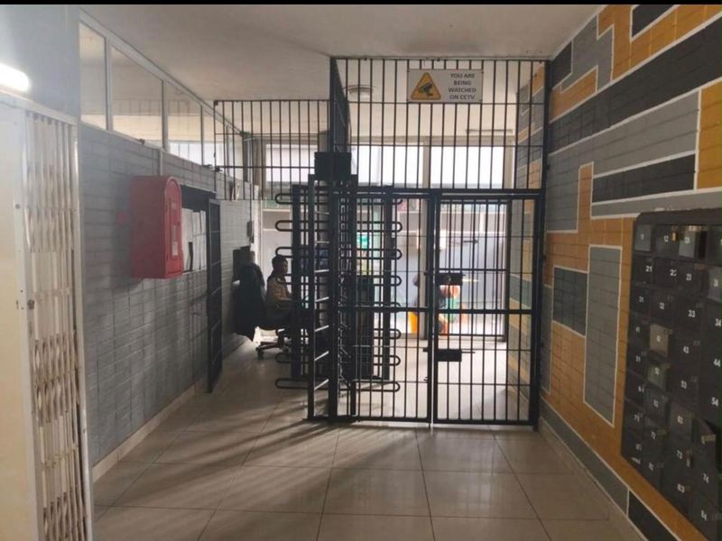 Building entrance lobby featuring a secure turnstile access point, wall-mounted fire safety equipment, and a bank of resident mailboxes.