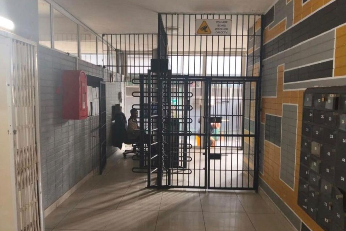 Building entrance lobby featuring a secure turnstile access point, wall-mounted fire safety equipment, and a bank of resident mailboxes.
