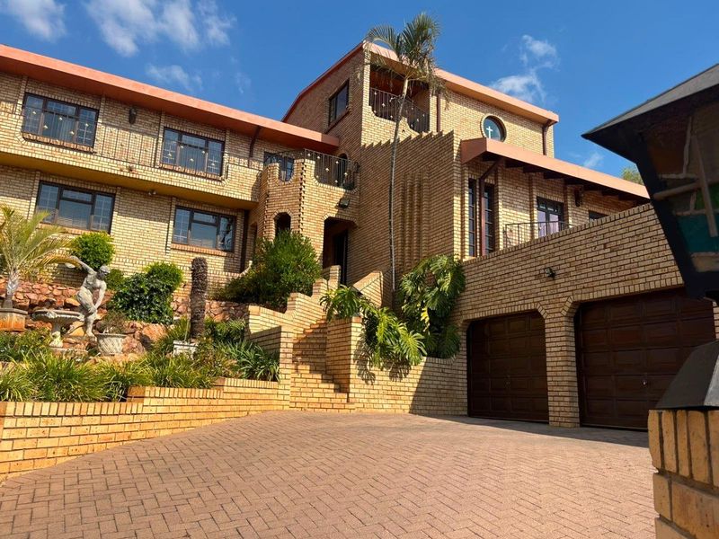 A multi-level face brick residence featuring a paved driveway, double garage, and elevated balconies with architectural brick detailing.