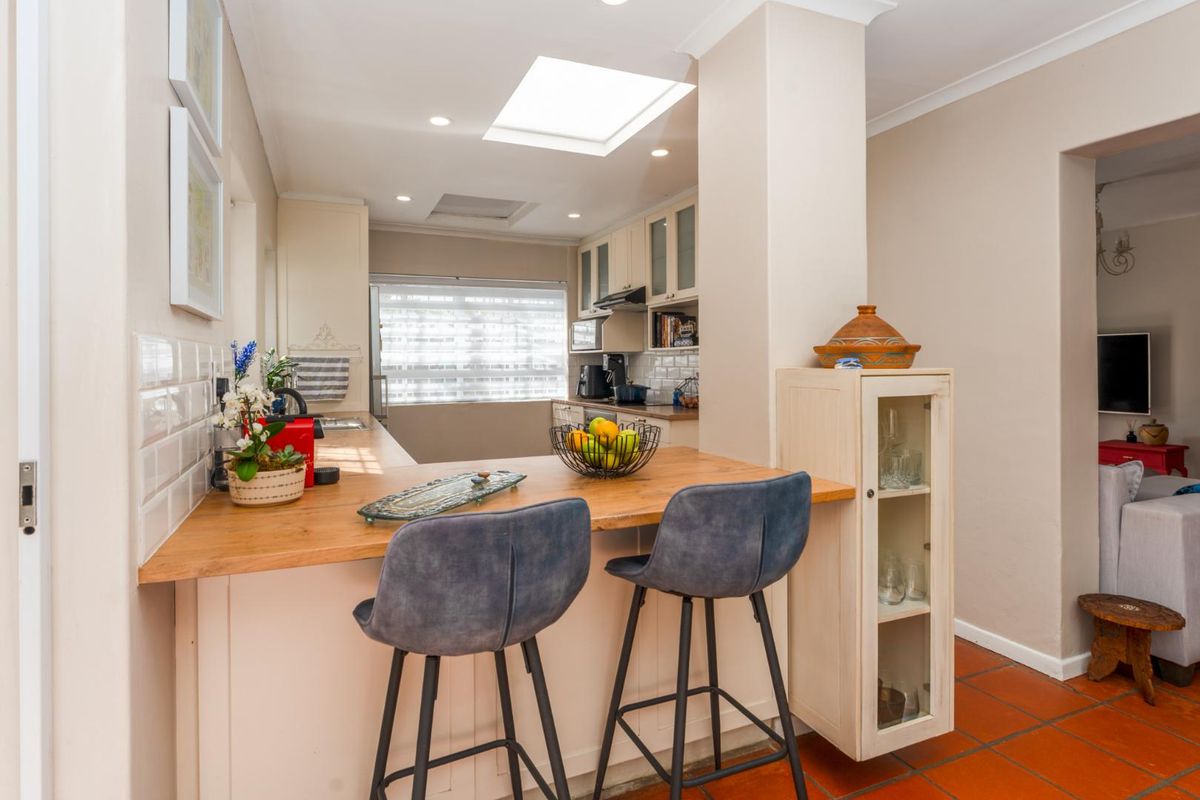 A functional kitchen featuring a wooden breakfast bar, subway tile backsplash, built-in cabinetry, and a skylight providing natural light.