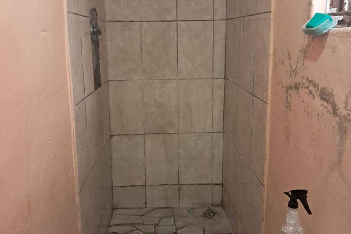 A small bathroom featuring a tiled shower enclosure and a standard toilet, requiring maintenance and cosmetic updates to the wall finishes.