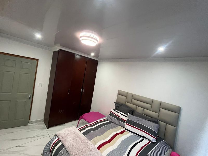 A well-maintained bedroom featuring glossy ceiling finishes, recessed lighting, tiled flooring, and a large built-in wardrobe.