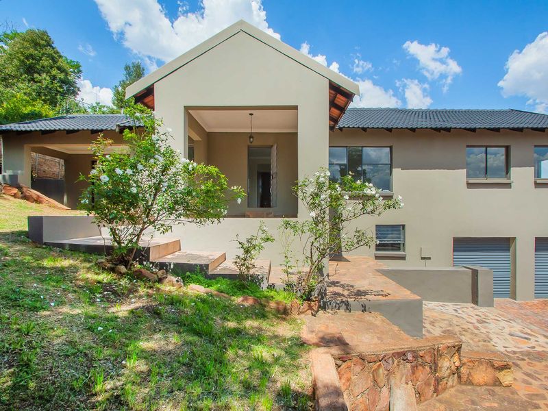 A well-maintained modern home featuring a covered entrance, double garage, and attractive stone landscaping with a paved driveway.