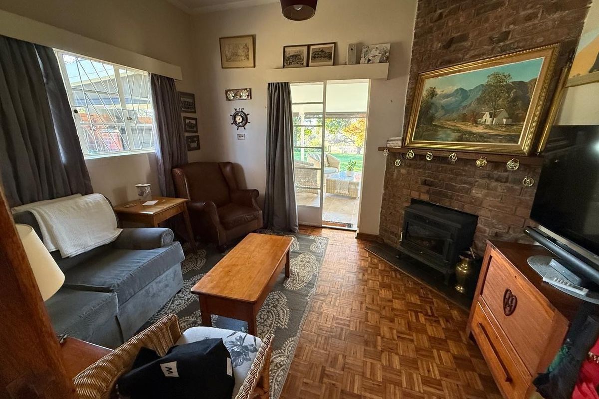 Cozy living room featuring a rustic brick fireplace with a built-in wood-burning stove, parquet flooring, and direct access to an outdoor patio area.