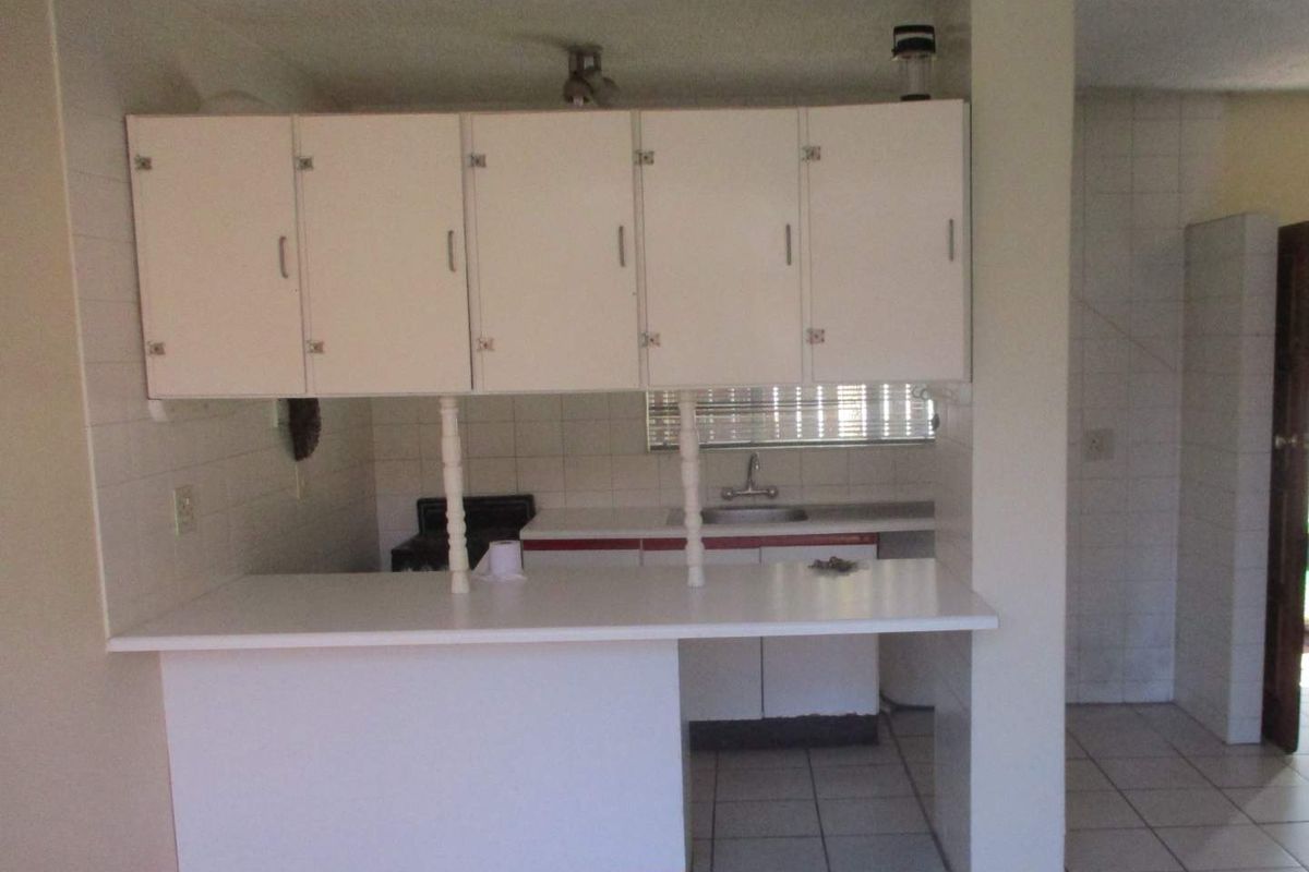 A dated kitchen featuring white built-in cabinetry, a breakfast bar, and tiled flooring, offering a functional layout ready for modern renovation.