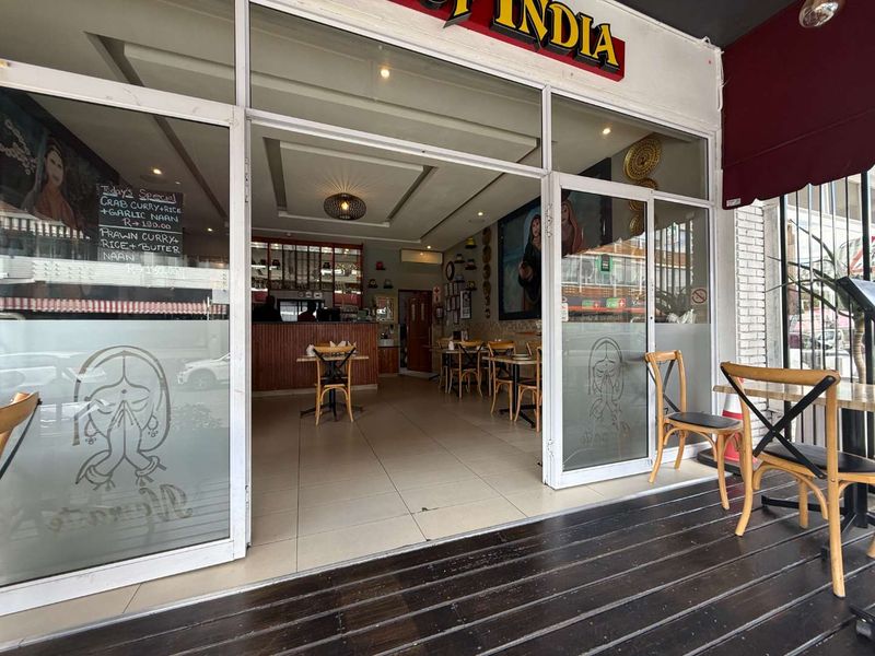 Entrance view of a retail restaurant space featuring a glass storefront, tiled interior flooring, and an outdoor wooden deck area.