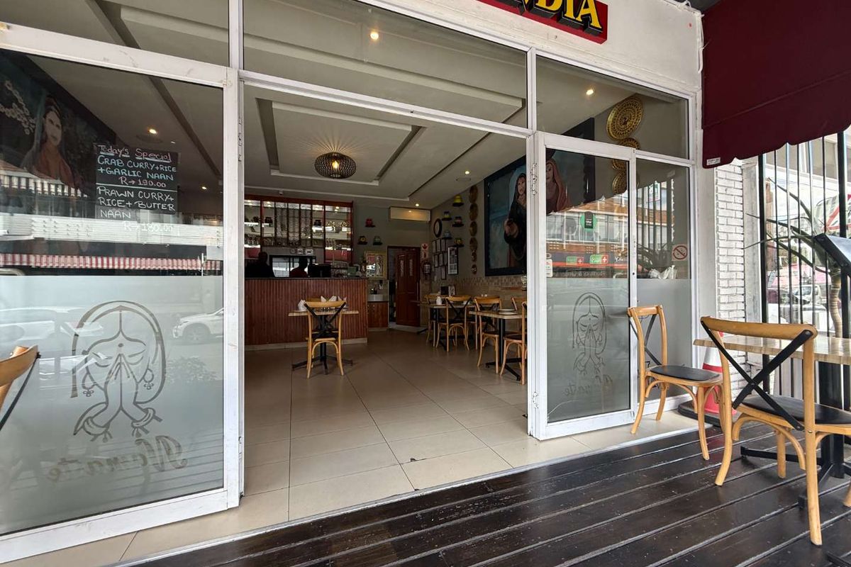 Entrance view of a retail restaurant space featuring a glass storefront, tiled interior flooring, and an outdoor wooden deck area.