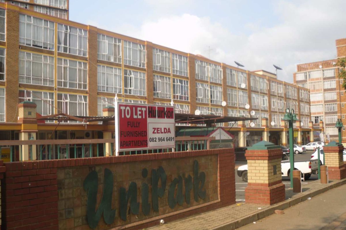 Front exterior view of the Unipark multi-story commercial or residential building featuring a brick facade and a prominent entrance boundary wall.