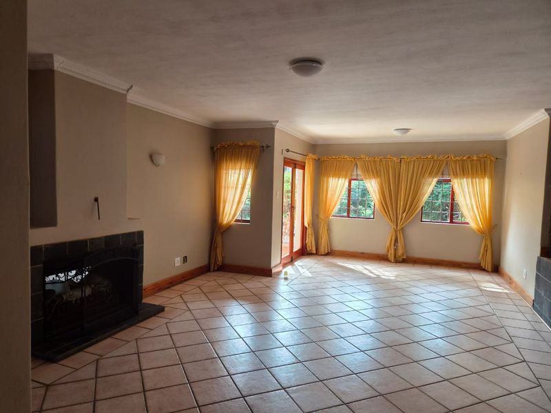 Spacious living room featuring tiled flooring, a built-in fireplace, crown molding, and large windows providing natural light with access to the outdoor area.