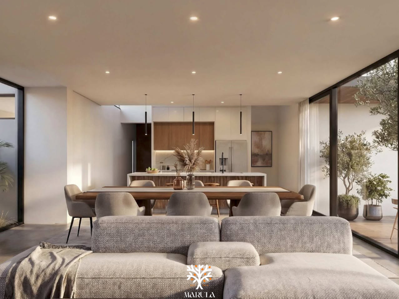 Modern open-plan living and dining area featuring a sleek kitchen with island, recessed lighting, and large sliding glass doors opening to an outdoor space.